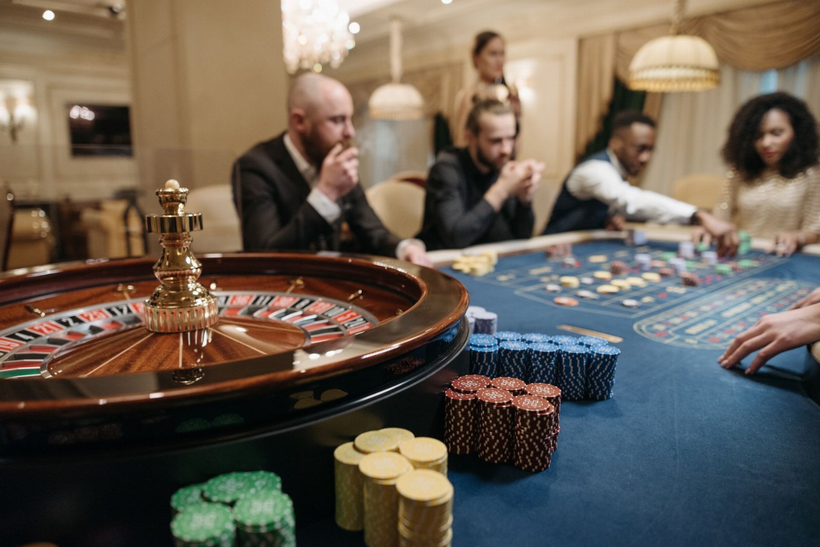 mejores paginas de apuestas y casino — People enjoying a roulette game in an upscale casino setting with chips and a roulette wheel.